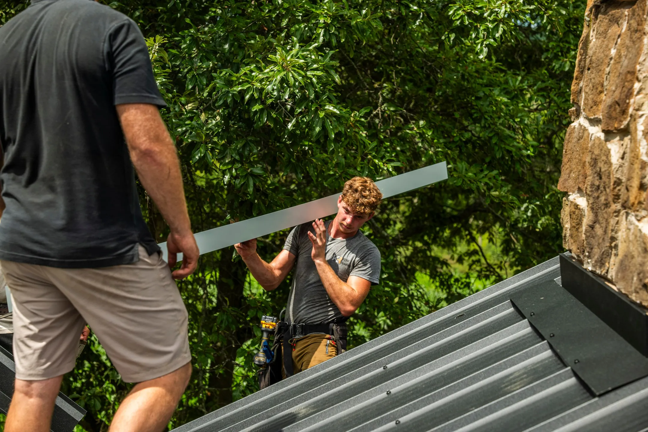 workers installing gray corrugated metal roofing