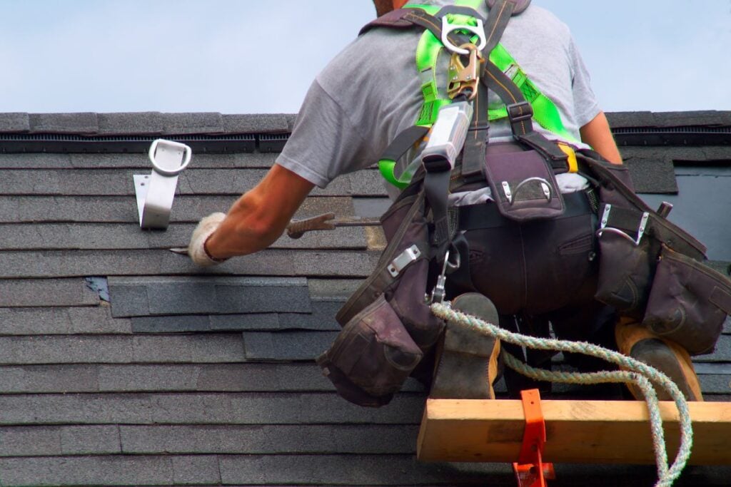 roofing tools worker on top of roof installing new shingles