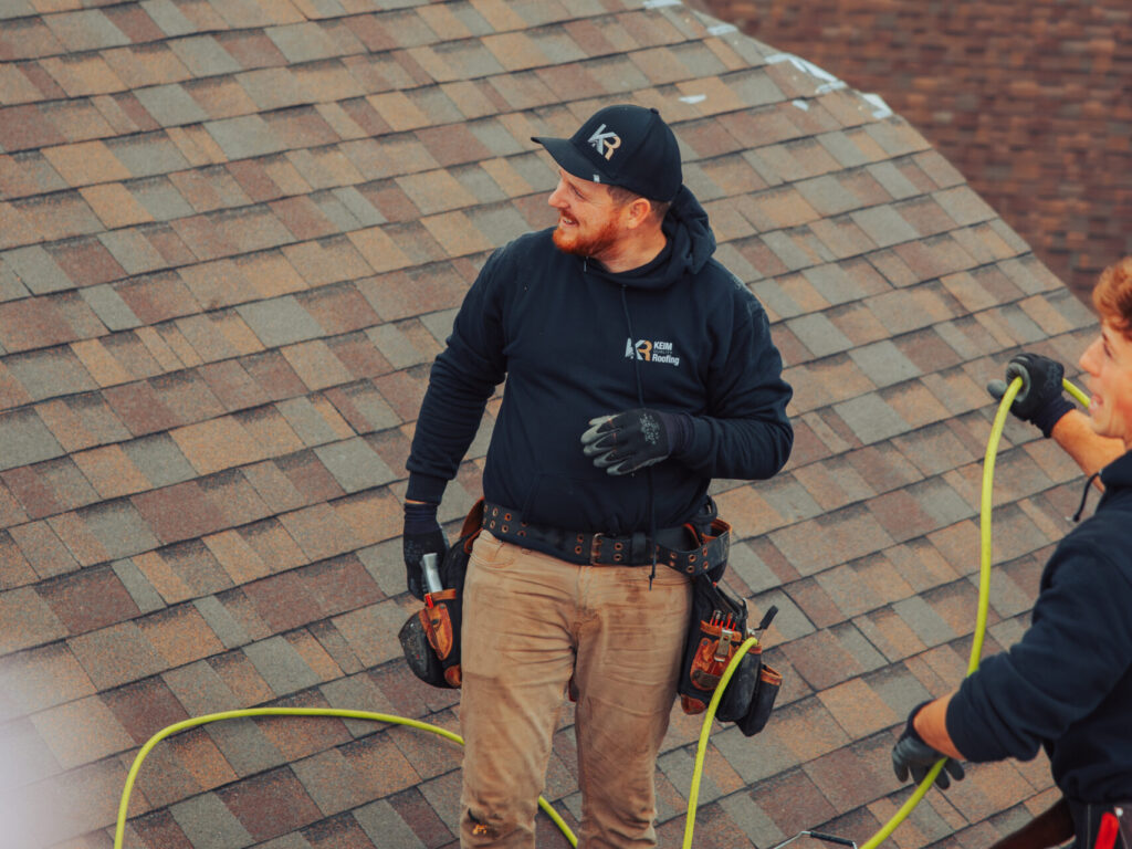 does home insurance cover roof repair Keim Quality Roofing worker on top of shingles roof